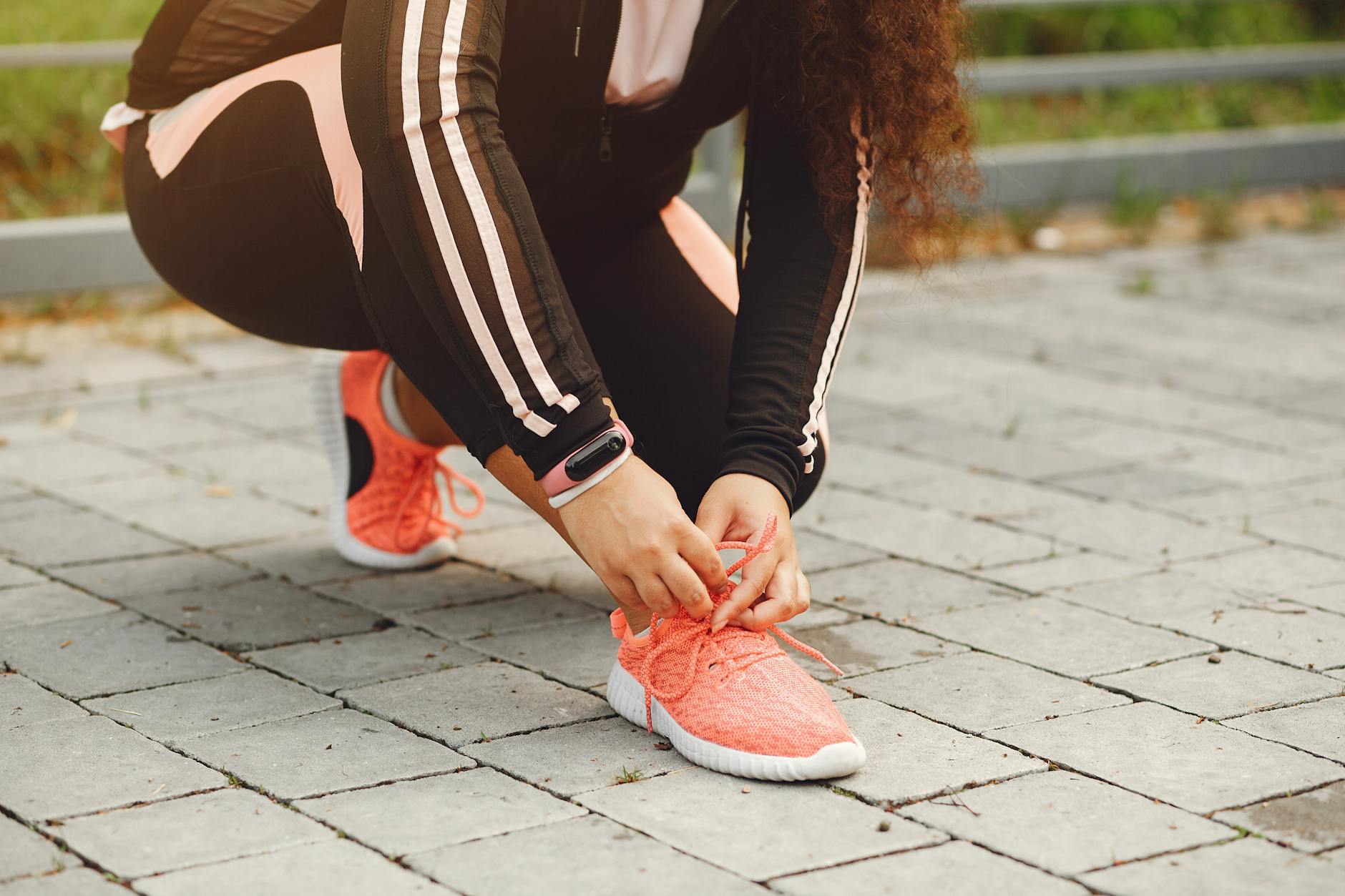 woman in sports clothing tying her running shoe